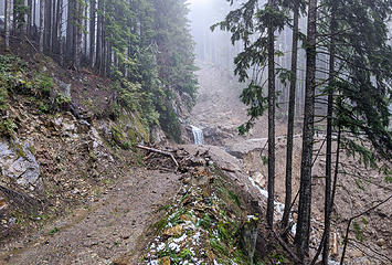 Back to mud flow above third switchback. The rocky waterfall ledge is what remains of the pretty waterfall by the road here. Map: location 5