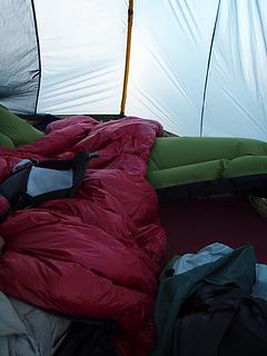 crowded tent with backpacks, pads, and bags