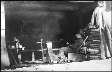 Man reading by the fire on a snowy day at the Pelton Creek Shelter on the Queets River. NPS image. Courtesy Henry Bonham. (BON.001.019)