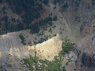 Looking across the valley of Glacier Creek, a sizeable patch of lighter-colored material stands out,  referred to as the Chromatic Moraine.  It looks like it is sun-lit, but not so much. The yellow band is hydrothermally-altered, sulphur-rich tephra, called YP tephra. It erupted from Sherman Crater, not the summit crater of Baker, in 1843. How did it get to this opposite side of Mount Baker? Kevin Scott and USGS colleagues believe it was blasted out of Sherman Crater as a damp mass during phreatic, or steam-rich, eruption(s), blew over the summit of Baker, and plopped down on the glacier surface. It was carried down the glacier in conveyor-belt fashion and eventually plastered against the moraine. Note that it is not a layer [i:ad231954ba]within[/i:ad231954ba] but is inset [i:ad231954ba]against[/i:ad231954ba] the moraine. The deposit is nowhere as thick as it appears. The apparent thickness is because the distinctively colored ash washes down the moraine walls as  a thin veneer.