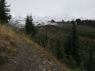 Round the crest of the Railroad Grade moraine and behold the deglaciated valley of Rocky Creek. The inner margin of Railroad Grade stretches toward Mount Baker, and across the valley the parallel left-lateral moraine (Metcalf moraine) matches.  At its maximum recent extent in the 1800s, you would have stepped off the moraine onto the glacier here. The ice surface reached the crest of these  paired moraines ('rocks don't fall uphill':), filled the valley at  your feet, and reached nearly to the lower crossing of Rocky Creek. The high mound in the center of the valley is an eroded remnant of a Mt. Baker lava flow, almost completely covered by glacial till.  Note Colfax and Lincoln Peaks, highest remnants of the extinct Black Buttes volcano, to left of the lurking Mt. Baker and Sherman Peak. At far right is Crag View, consisting of  late Mt. Baker lavas. Clouds obscured all of these peaks ten minutes later.