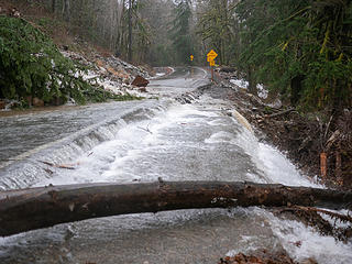 Water sheeting over the chip seal road and washing away the bank below