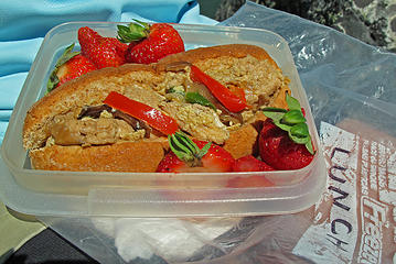 Strawberries and chicken sandwich garnished with red pepper.