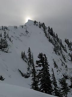 Clouded sun behind the corniced crest