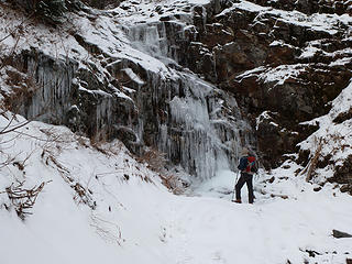 Hiker at frozen waterfall on McClellan Butte.
