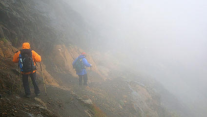 Hikers, fog and orange vein in rock
