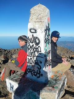 two friends sitting on the summit in different countries
