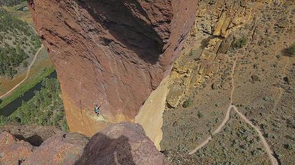 Hikers can be seen on the approach trail as the second, safely belayed from above, prepares to launch...