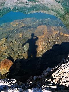 Shadow on rocks under the water in a lake reflecting a mountain